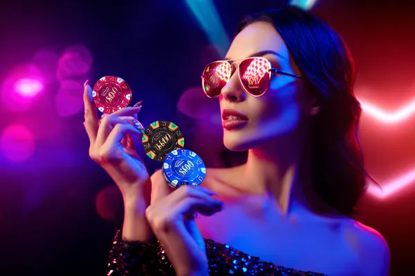 A woman smiling while playing online games on her laptop, surrounded by neon casino elements, showcasing 786BET’s diverse game collection.